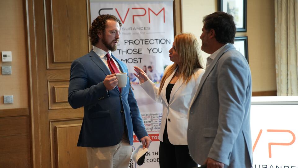 Three guests networking beside an event sponsor banner