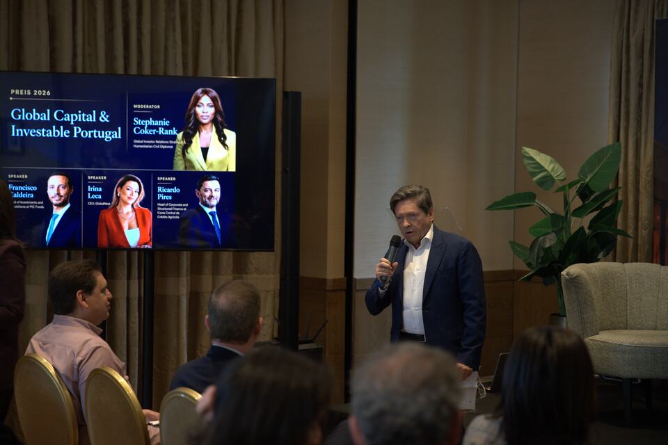 A speaker addressing the PREIS audience beside the programme screen